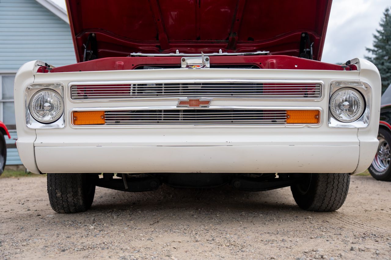 contact-img Close-up of a vintage Chevrolet pickup's front, displaying its distinctive grill and open hood.