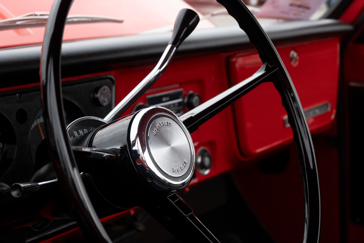 why-choose-us Close-up view of a classic Chevrolet steering wheel in a vintage red truck in Alto, Michigan.