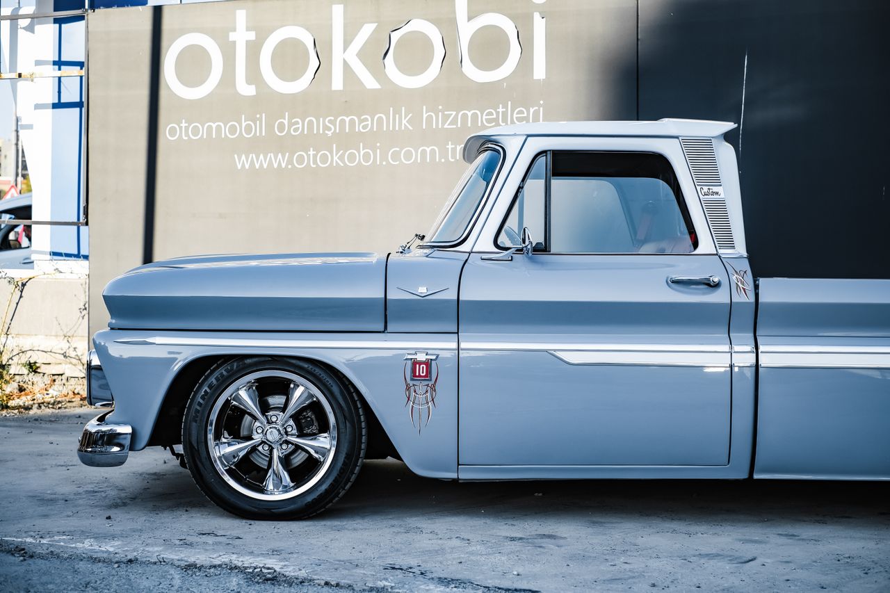 services-img Side view of a classic blue pickup truck parked in front of an Otokobi sign.