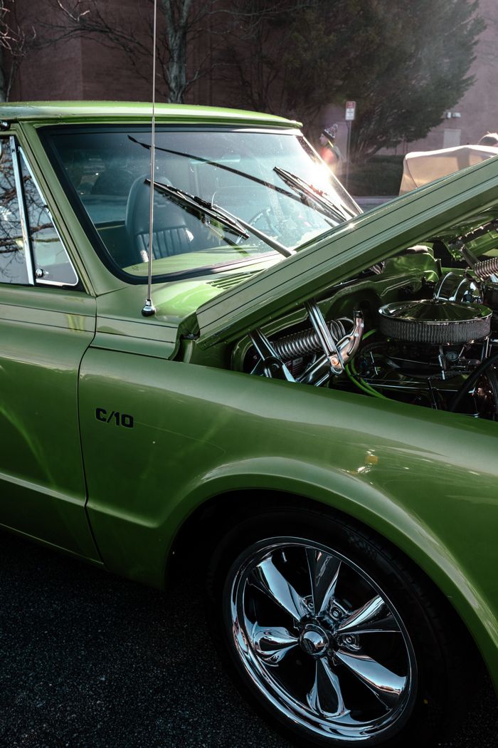 about-01 Close-up of a vintage green C10 pickup truck with its hood open revealing the engine.