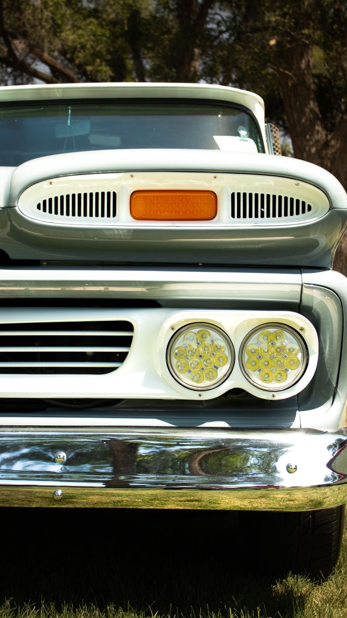 gallery-5 Detailed view of a classic vintage truck's front grill and headlights outdoors.